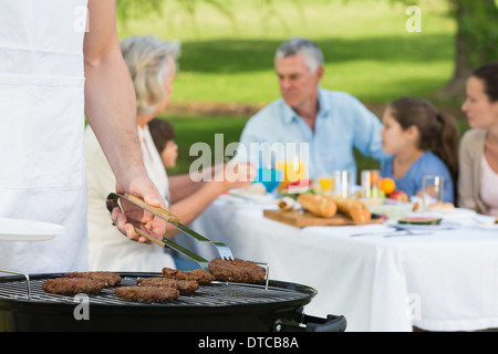 Barbecue grill with extended family having lunch in park Stock Photo