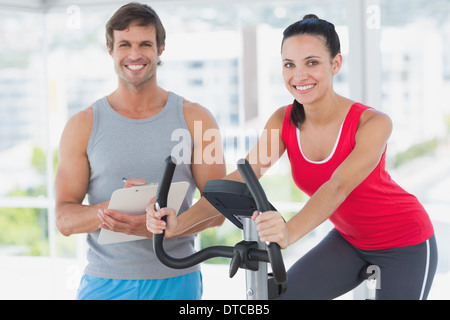 Woman with instructor working out at spinning class in bright gym Stock Photo