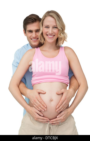 Expectant happy parents making a heart shape on mothers baby bump Stock Photo