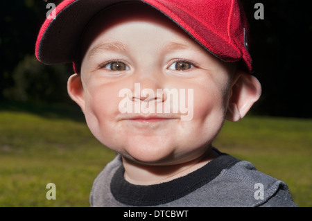 A 14-month-old Caucasian toddler wearing a red hat has his portrait taken in Prospect Park in Brooklyn, NY. Stock Photo