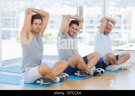 Men stretching on mats in fitness class Stock Photo