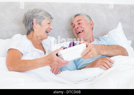 Senior couple holding gift box in bed Stock Photo