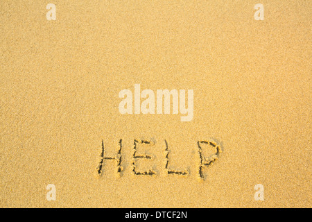 Help - written in sand on beach texture. Stock Photo