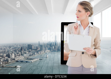 Composite image of pensive blonde businesswoman holding clipboard Stock Photo