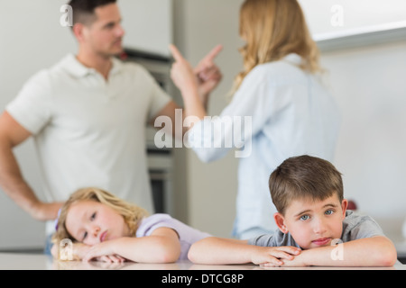 Children leaning on table while parents arguing Stock Photo