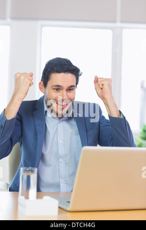 Businessman with clenched fists using laptop Stock Photo