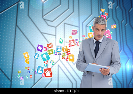 Composite image of serious businessman using tablet pc looking at camera Stock Photo