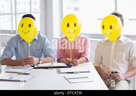 Business people holding balloons in front of face Stock Photo