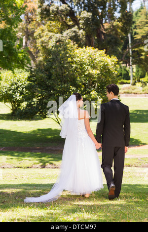 Rear view of newlywed couple walking in park Stock Photo
