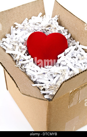 Red plush heart in an open cardboard box with shredded paper around it Stock Photo