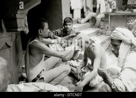 Ritual funeral haircut at Manikarnika cremation ghat Varanasi Benares in Uttar Pradesh in India in South Asia. Reportage Death River Ganges Travel Stock Photo