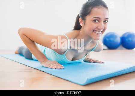 Smiling beautiful woman doing push ups in gym Stock Photo