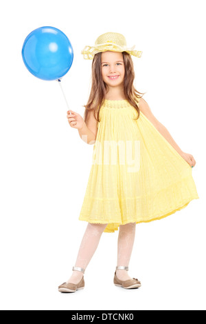 Full length portrait of an adorable little girl in yellow dress holding a blue balloon Stock Photo