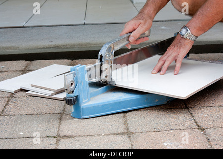 a male tiler cutting ceramic tiles with a tile cutter Stock Photo