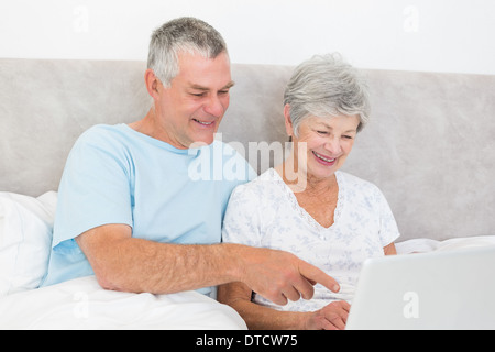 Senior couple using laptop in bed Stock Photo