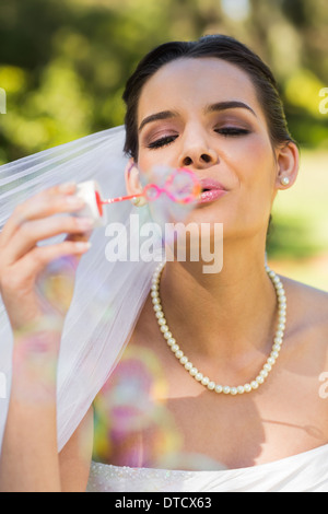 Beautiful bride blowing soap bubbles in park Stock Photo