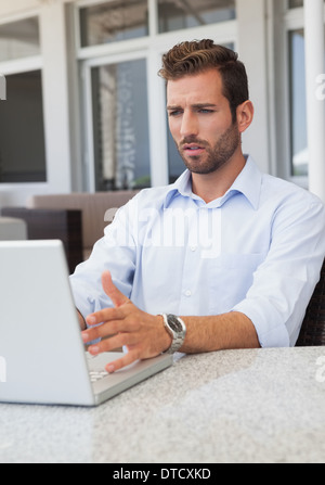 Stressed businessman working on laptop at table Stock Photo