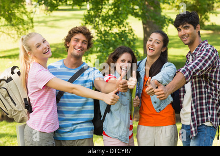 College friends gesturing thumbs up in campus Stock Photo