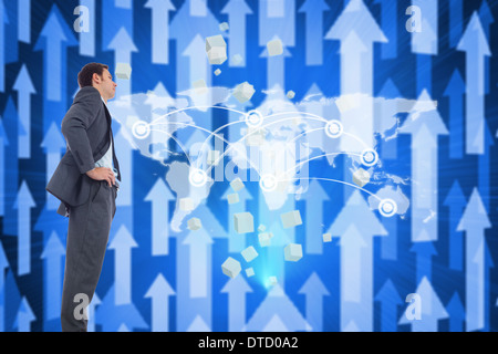 Composite image of serious businessman with hands on hips Stock Photo