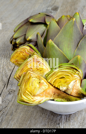fresh raw whole artichokes on wooden table background Stock Photo