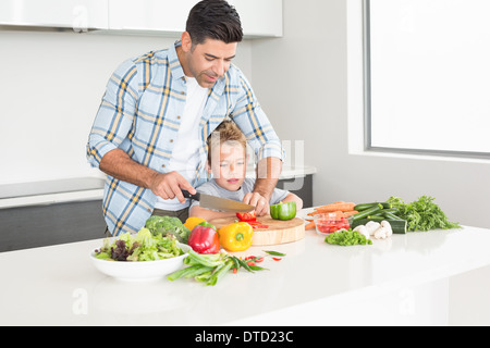 Father teaching his son how to chop vegetables Stock Photo