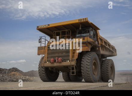 A large Caterpille mining truck hauls waste to the dump in a massive open pit copper and gold mine in Africa Stock Photo