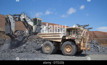 I Liebherr mining excavator/ digger loads a white hitatchi hybrid haul truck with waste in a large open cast African copper mine Stock Photo