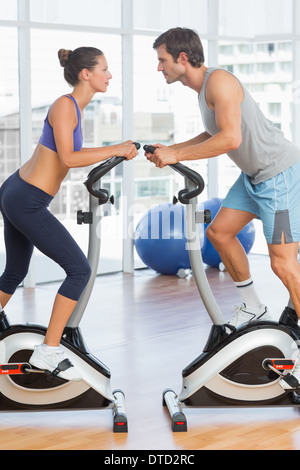 Side view of a couple working at spinning class in gym Stock Photo