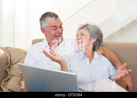 Loving senior couple with laptop on sofa Stock Photo