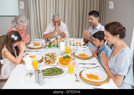 Family of six saying grace before meal at dining table Stock Photo