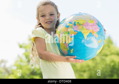 Cute young girl holding globe at park Stock Photo