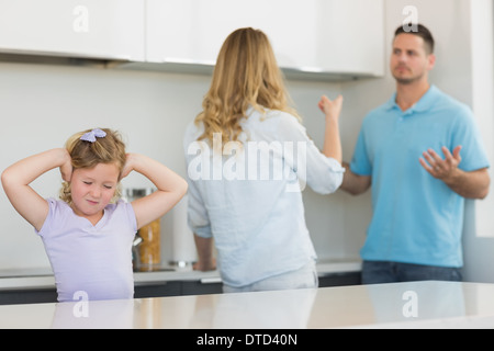 Girl covering ears while parents arguing Stock Photo