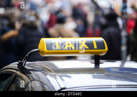 Taxi car in town center crowded with pedestrians Stock Photo