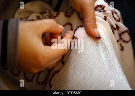Color shot of two hands holding a needle and sewing  Stock Photo