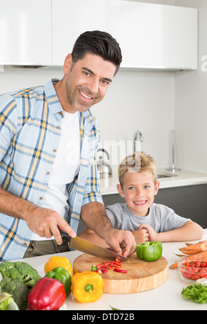 Happy father teaching his son how to chop vegetables Stock Photo