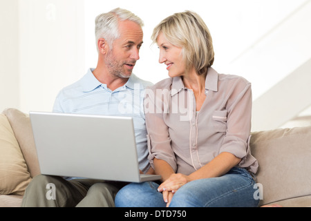 Happy mature couple using laptop on sofa Stock Photo