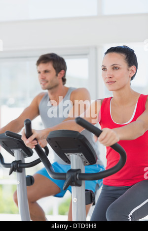 Determined couple working out at spinning class in gym Stock Photo