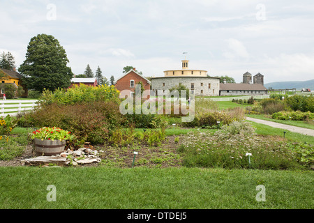 Beautiful round stone  barn at the Hancock Shaker Village in Massachusetts.  Herbs, flowers and vegetables grow in foreground. Stock Photo