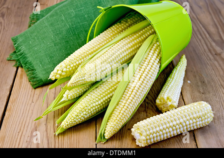 Corn on the cob with green bucket and napkin on the background of wooden boards Stock Photo