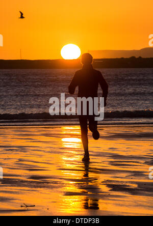 Jogger on beach at sunrise. North Gare beach near Seaton Carew, north east England. UK Stock Photo
