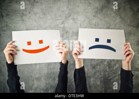 Happy and sad face. Women holding papers with happy and sad emoticons. Stock Photo