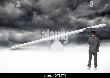 Composite image of rear view of classy businessman holding grey umbrella Stock Photo