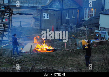 Birling Gap, East Sussex, UK. 16th February  2014. Couple leave their holiday home due to the storms. Happy memories up in smoke as erosion due to storms forces family to leave their holiday cottage on the Sussex Coast. Mr and Mrs Oaten have owned the end cottage for 5 years and hoped for another 5 years use but relentless storms on the South coast has brought the cliff edge to within a meter of the property so they have decided it is time to leave. Accumulated furniture and the old garden shed being burned Credit:  David Burr/Alamy Live News Stock Photo