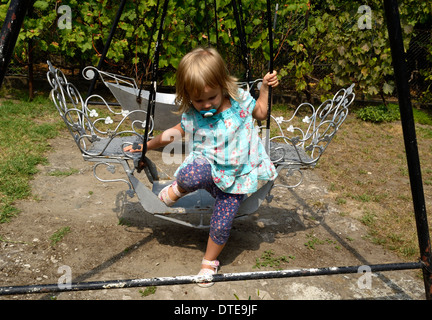 Little girl on the swing in blue dress Stock Photo