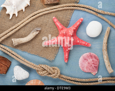 Seashells, ship rope and burlap over wooden background Stock Photo