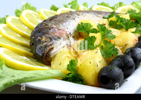 Grilled trout with potato, salad, black olives, lemon, close up Stock Photo