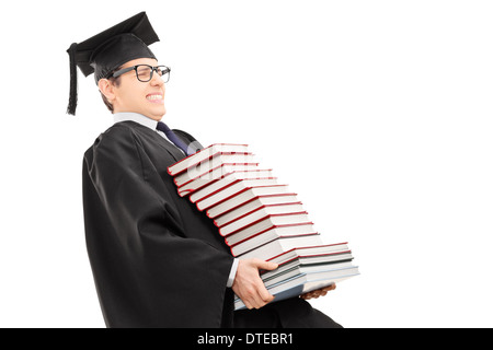 Young man in graduation gown carrying bunch of books Stock Photo