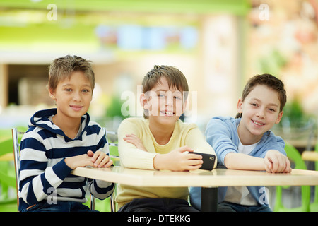 Portrait of three schoolboys sitting at table Stock Photo