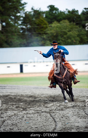 A cowboy on a horse riding at full gallop with pistol drawn. Annie Oakley Boom Days Festival in Pinehurst North Carolina. Stock Photo