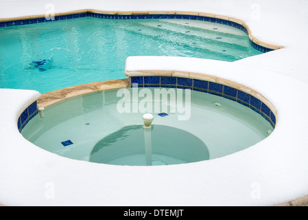 Outdoor hot tub or spa by swimming pool surrounded by snow in the winter Stock Photo